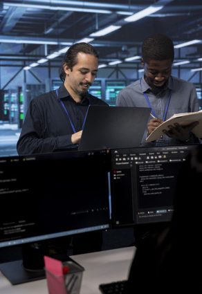 Dos profesionales colaborando en un centro de datos frente a pantallas y servidores, simbolizando soluciones híbridas en la nube de Elita Projects