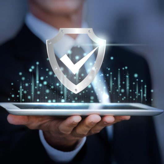 Profesional sosteniendo una tableta con un ícono de escudo y check, representando protección integral y seguridad avanzada en el desarrollo de software.